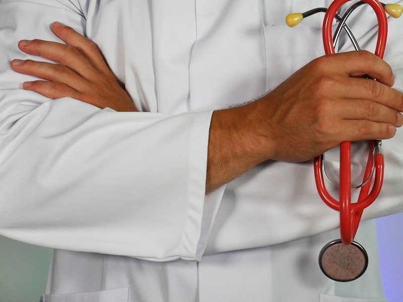 Cropped portrait of a clinician in white coat holding a stethoscope — clinical thyroid and adrenal evaluation